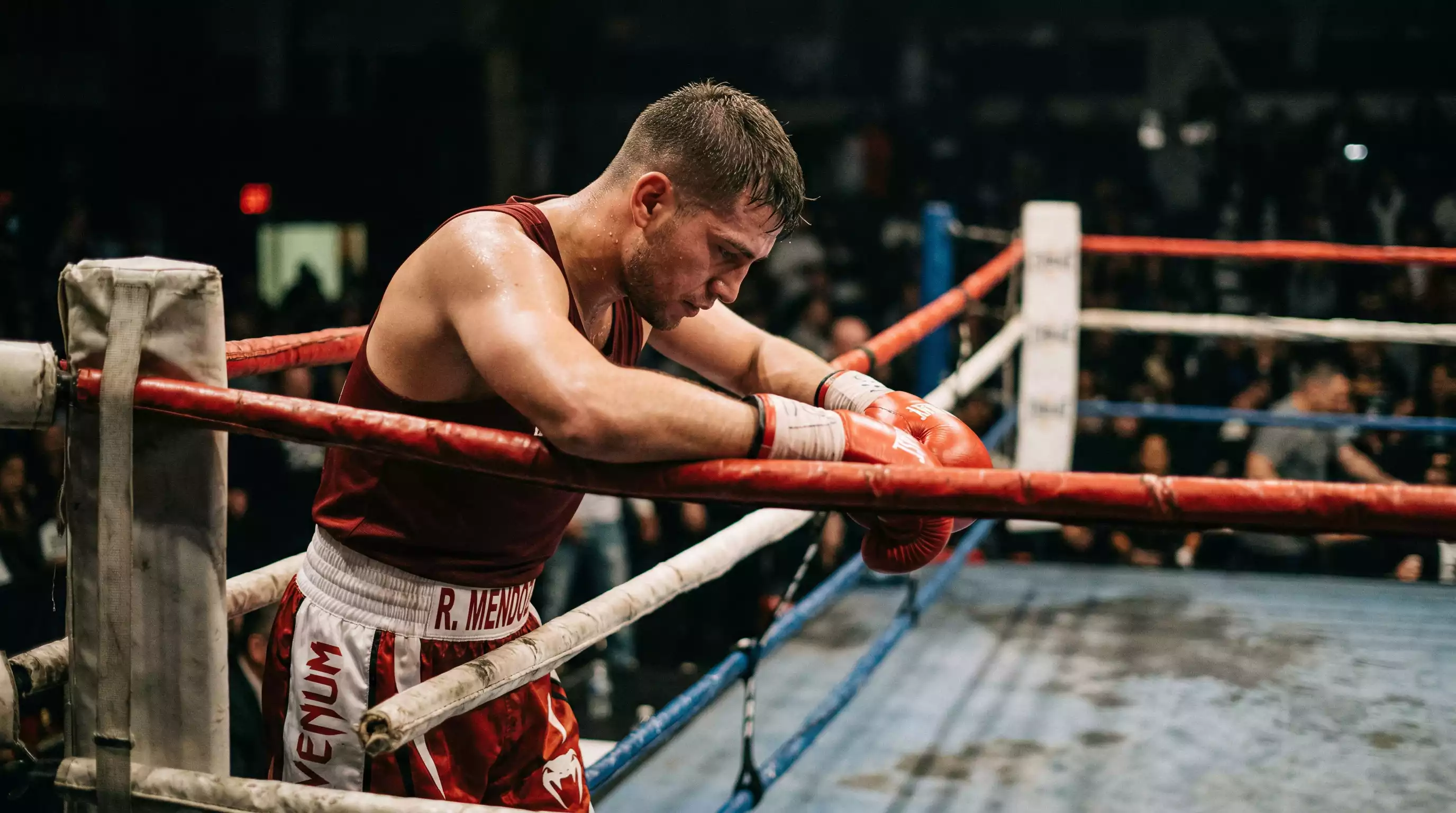 Boxer stützt sich nachdenklich auf die Ringseile nach einer schwierigen Runde